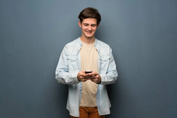 Hombre Adolescente Con Chaqueta Jean Sobre Pared Gris Enviando Mensaje —  Fotos de Stock