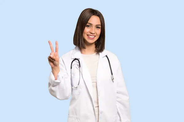 Giovane Donna Medico Sorridente Mostrando Segno Vittoria Sfondo Blu Isolato — Foto Stock