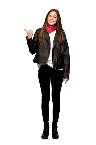 孤立した白い背景に製品を提示する側を指している革のジャケットを持つ若い女性のフルレングスのショット — ストック写真