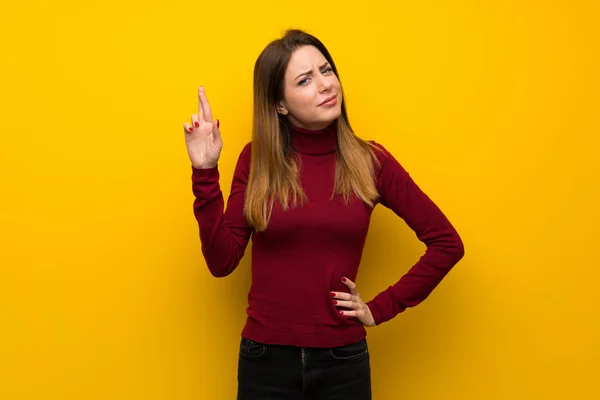 Wanita Dengan Turtleneck Atas Dinding Kuning Dengan Jari Jari Menyeberang — Stok Foto