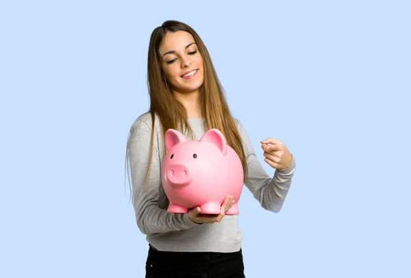 Young Girl Holding Piggybank Blue Background — Stock Photo, Image