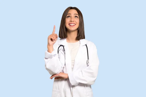 年轻的医生妇女指向与食指一个伟大的想法在被隔绝的蓝色背景 — 图库照片