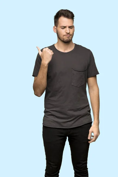 Man Met Zwarte Shirt Ongelukkig Wijst Naar Kant Blauwe Achtergrond — Stockfoto