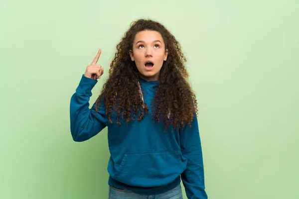 Adolescente Menina Sobre Parede Verde Pensando Uma Ideia Apontando Dedo — Fotografia de Stock