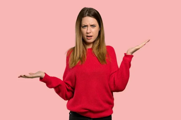 不幸な赤いセーターを持つ若い女性から分離 ピンクの背景の上に何かを理解していません — ストック写真