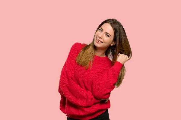 分離ピンク背景微笑む赤いセーターを持つ若い女性 — ストック写真