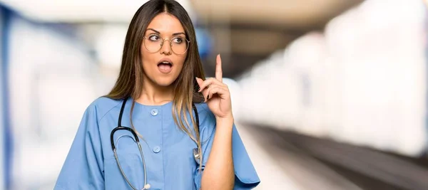 Jovem Enfermeira Pensando Uma Ideia Apontando Dedo Para Cima Hospital — Fotografia de Stock