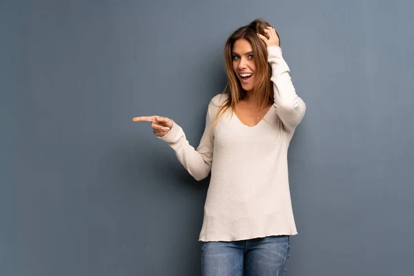 Mujer Rubia Sobre Fondo Gris Sorprendida Señalando Dedo Hacia Lado — Foto de Stock