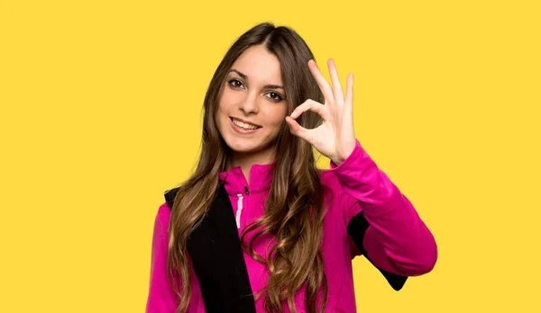 Junge Sportlerin Zeigt Ein Zeichen Mit Den Fingern Über Gelbem — Stockfoto