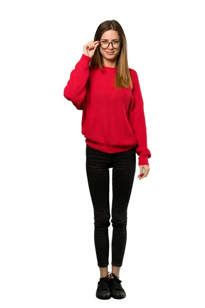 メガネと分離の白い背景にびっくりの赤いセーターを持つ若い女性のフルレングス ショット — ストック写真