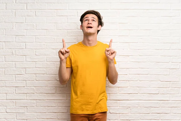 Adolescente Homem Sobre Parede Tijolo Branco Surpreso Apontando Para Cima — Fotografia de Stock