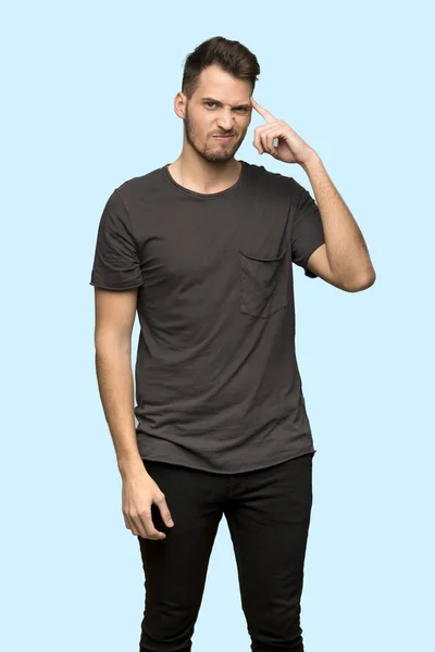 青い背景の上 頭に指を置いての狂気のジェスチャーを作る黒いシャツを持つ男 — ストック写真
