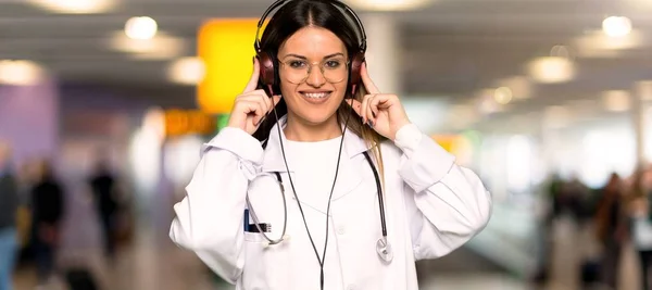Young doctor woman listening to music with headphones in a hospital