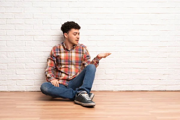 Mladý Muž Sedí Podlaze Drží Copyspace Pochybnostmi — Stock fotografie