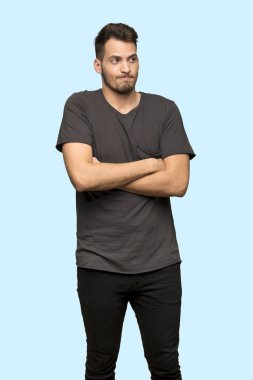 Adam siyah gömlek yapma ile jest omuzları üzerinde mavi arka plan kaldırma sırasında şüpheler