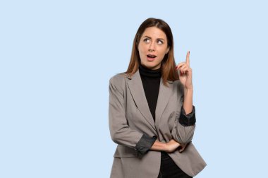 İş kadını izole mavi arka plan üzerinde parmak işaret bir fikir düşünüyorum