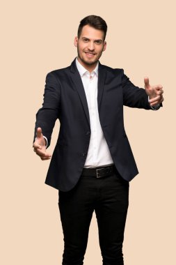 Sunulması ve koyu sarı arka plan üzerinde el ile gelmek davet yakışıklı iş adamı