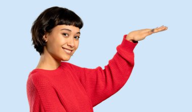 Kısa saç kız kırmızı kazaklı boşaltmak holding ile izole mavi zemin üzerine bir reklam eklemek için