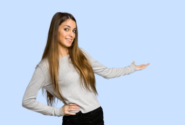 geri işaret ve mavi arka plan üzerinde bir ürün sunma genç kız