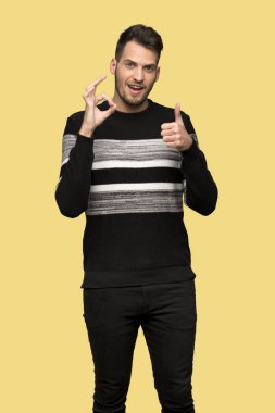Yakışıklı adam gösteren ok işareti ile ve sarı arka plan üzerinde bir başparmak yukarı hareketi vererek