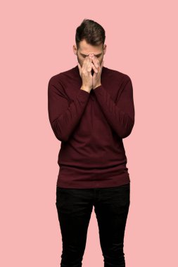 Adam yorgun ve hasta ifade üzerinde pembe bir arka plan ile balıkçı yaka kazak