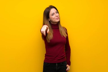 Kadın sarı duvarın üzerinden balıkçı yaka ile parmak seni kendinden emin bir ifadesiyle işaret