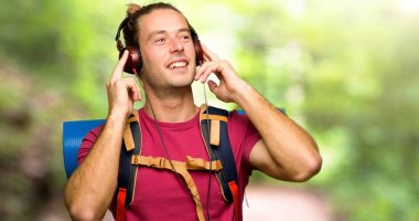Dağ kulaklık ile müzik dinlemek dağ backpacker adamla uzun yürüyüşe çıkan kimse