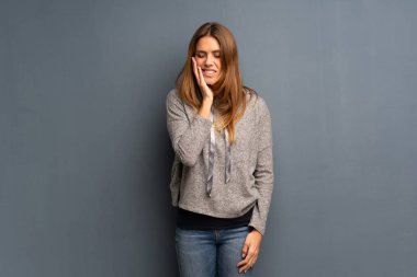 Diş ağrısı ile gri arka plan üzerinde sarışın kadın