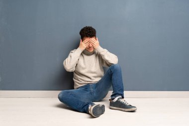 Gözleri eller tarafından kapsayan katta oturan genç adam