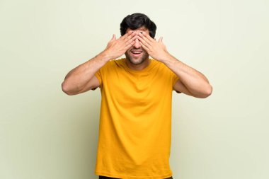 Pembe duvar eller tarafından gözleri kaplama genç adam. İleride ne olduğunu görmek için sürpriz