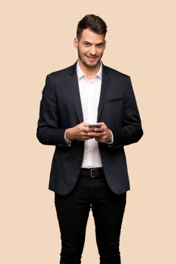 Yakışıklı iş adamı koyu sarı arka plan üzerinde mobil ileti gönderme