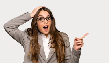 Parmak tarafına işaret ve izole gri arka plan üzerinde bir ürün sunan iş kadını