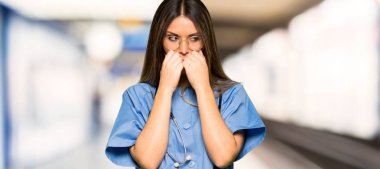 Biraz gergin ve korkmuş bir hastane ağzına ellerini koyarak genç hemşire