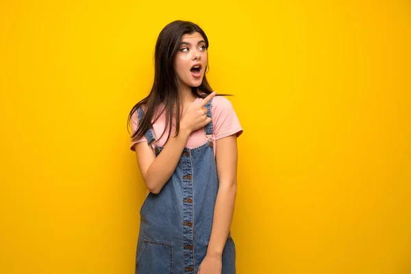 Adolescente Menina Sobre Parede Amarela Surpreendido Apontando Lado — Fotografia de Stock