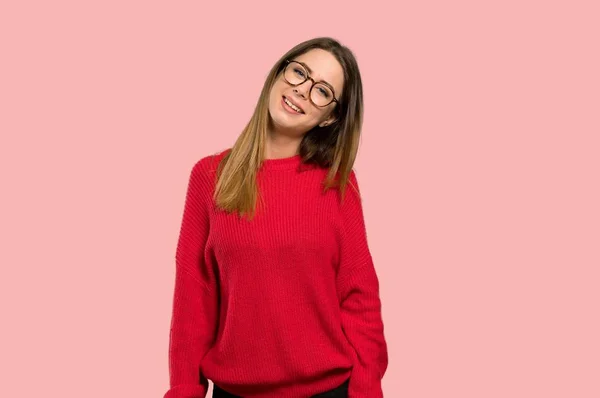 メガネと分離ピンク背景に満足して赤いセーターを持つ若い女性 — ストック写真