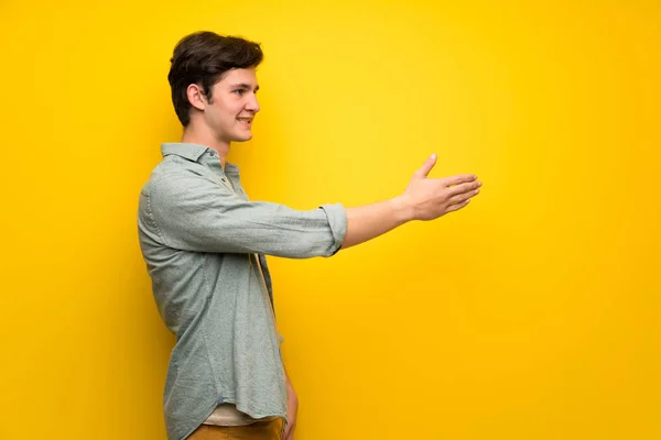 Adolescente Homem Sobre Parede Amarela Handshaking Após Bom Negócio — Fotografia de Stock