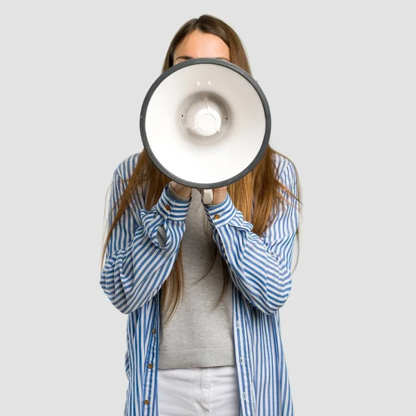 メガホンを使って叫んでいるストライプのシャツで若い女の子を孤立した灰色の背景の上に何かを発表 — ストック写真