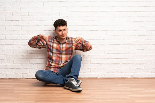 Mladý Muž Sedí Podlaze Zobrazeno Palec — Stock fotografie