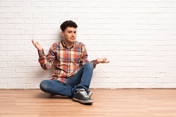 Mladý Muž Sedí Podlaze Nešťastný Něčemu Nerozumíte — Stock fotografie