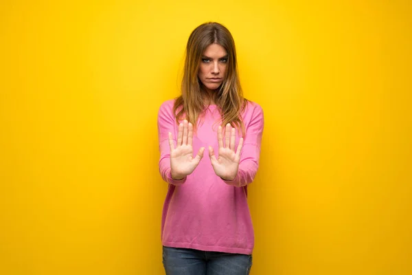 黄色の壁作る停止ジェスチャーと失望のピンクのセーターの女性 — ストック写真