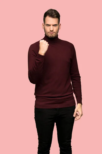 ピンクの背景に怒りの意思表示とタートルネックのセーターを持つ男 — ストック写真