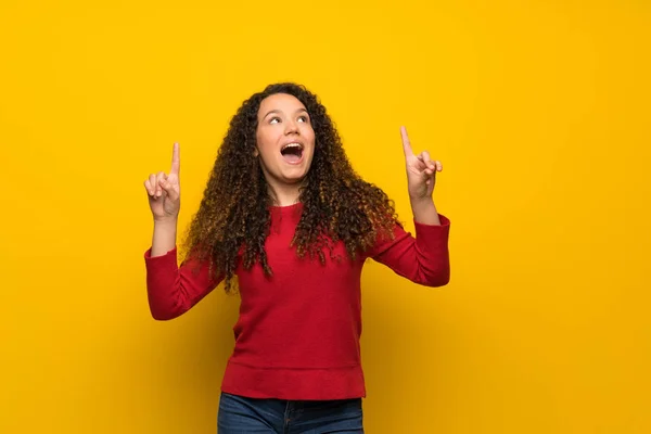 Adolescente Chica Con Suéter Rojo Sobre Pared Amarilla Sorprendida Apuntando — Foto de Stock