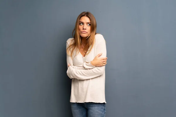 Mujer Rubia Sobre Fondo Gris Haciendo Gestos Dudas Mientras Levanta — Foto de Stock