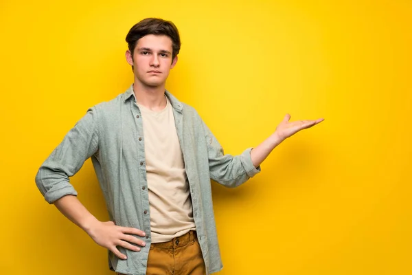 Mężczyzna Nastolatek Nad Żółte Ściany Trzymając Miejsce Wyobraźni Dłoni Wstawienia — Zdjęcie stockowe