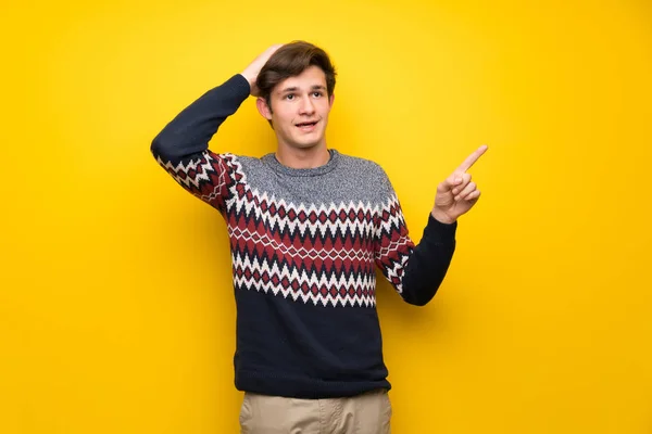 Nastolatek Mężczyzna Ponad Żółte Ściany Zaskoczony Wskazując Palcem Bok — Zdjęcie stockowe