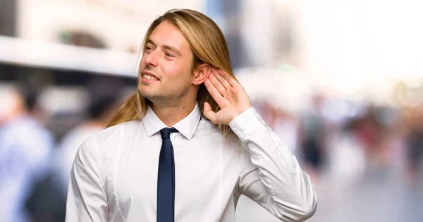 Blond Businessman Long Hair Listening Something Putting Hand Ear Outdoors — Stock Photo, Image