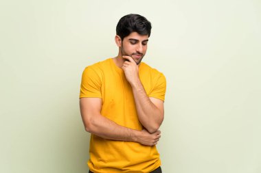 Genç adam pembe duvar çene üzerinde el ile bakıyor