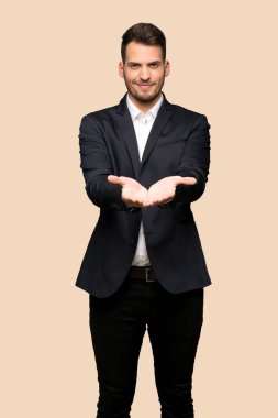 Yakışıklı iş adamı boşaltmak hayali avuç içinde tutarak koyu sarı arka plan üzerinde bir reklam eklemek için