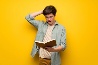 Genç adam sarı duvarın üzerinden bir kitap okuma tadını çıkarırken şaşırttı