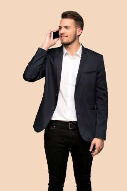 Cep telefonu ile bir görüşme koyu sarı arka plan üzerinde tutmak yakışıklı iş adamı